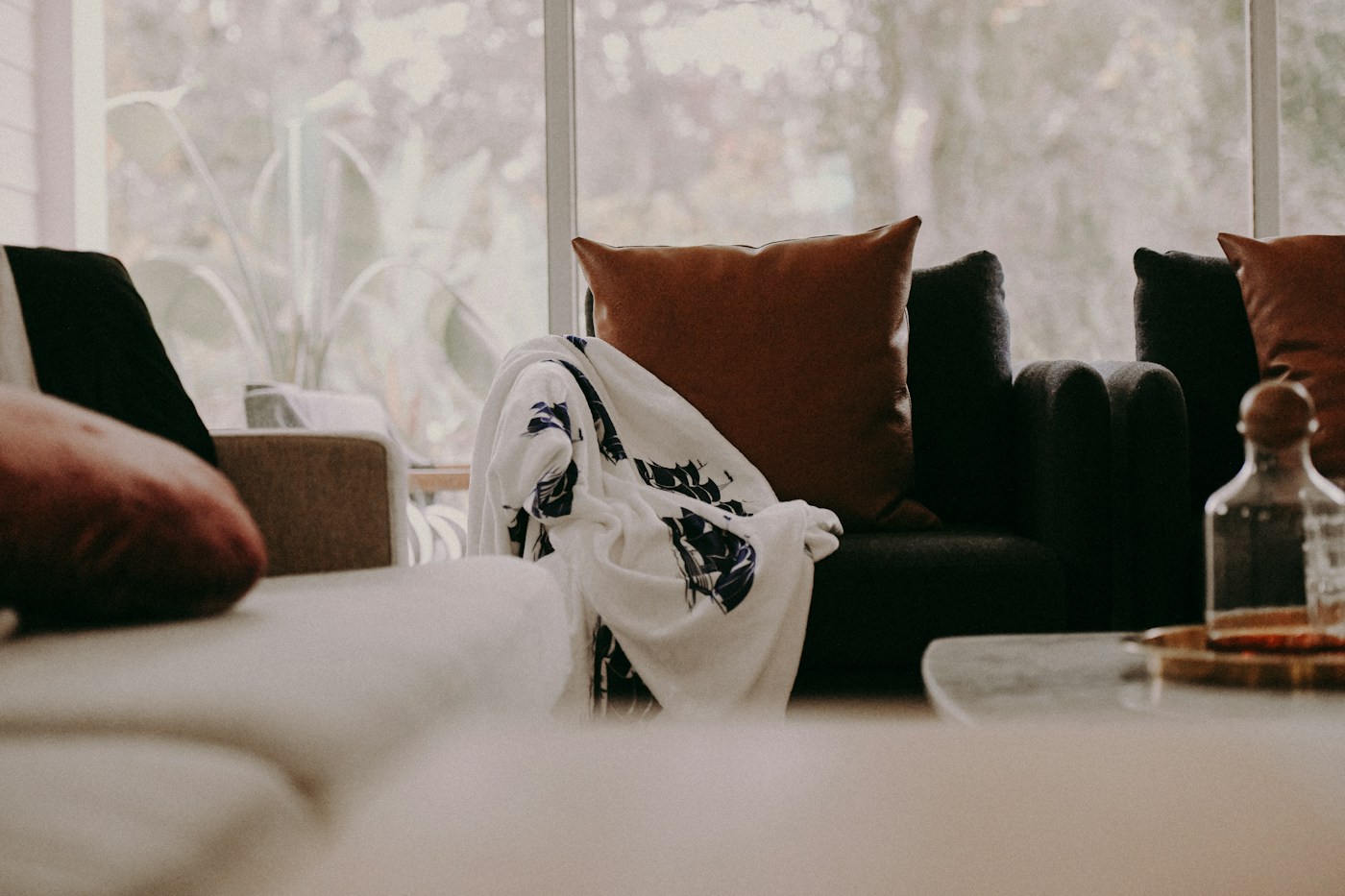 A cosy living room with a dark green sofa, natural fabrics and soft daylight